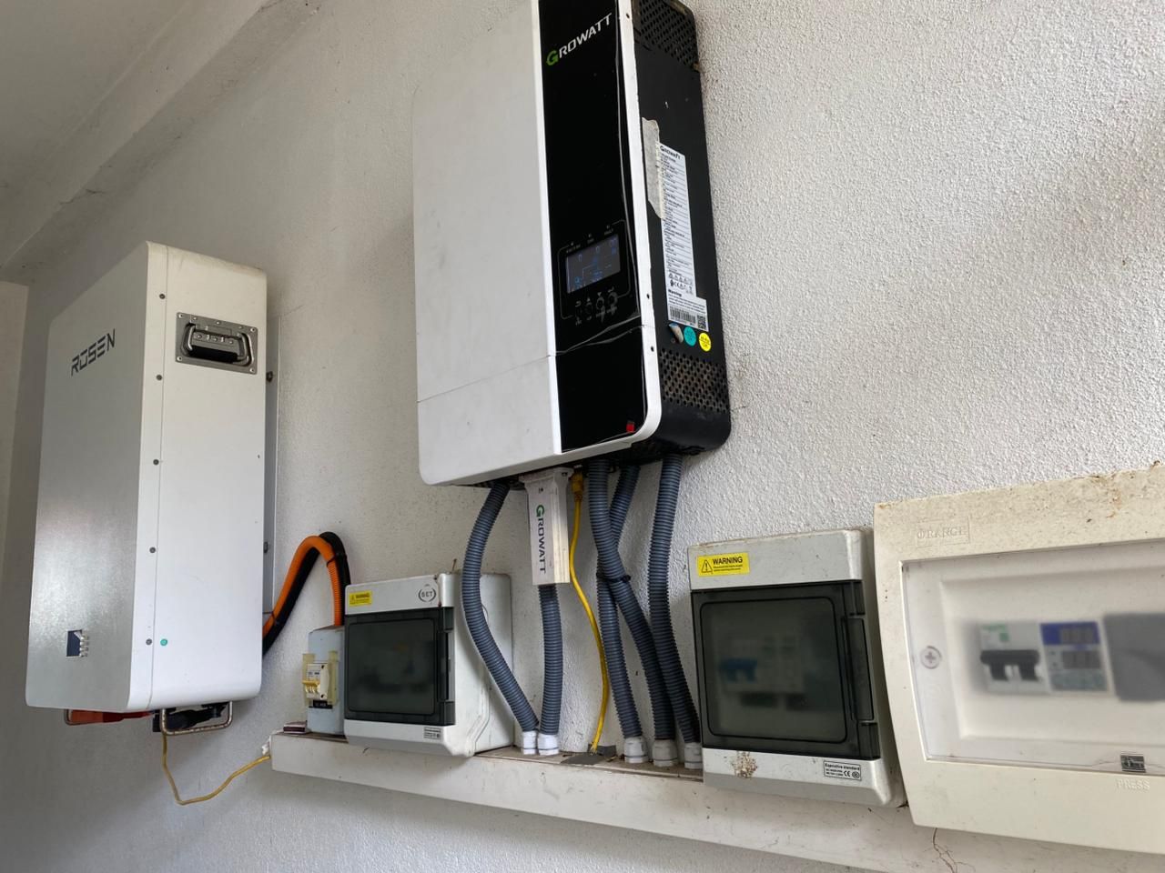 Growatt off-grid inverter beside a lithium battery cabinet and protection enclosures