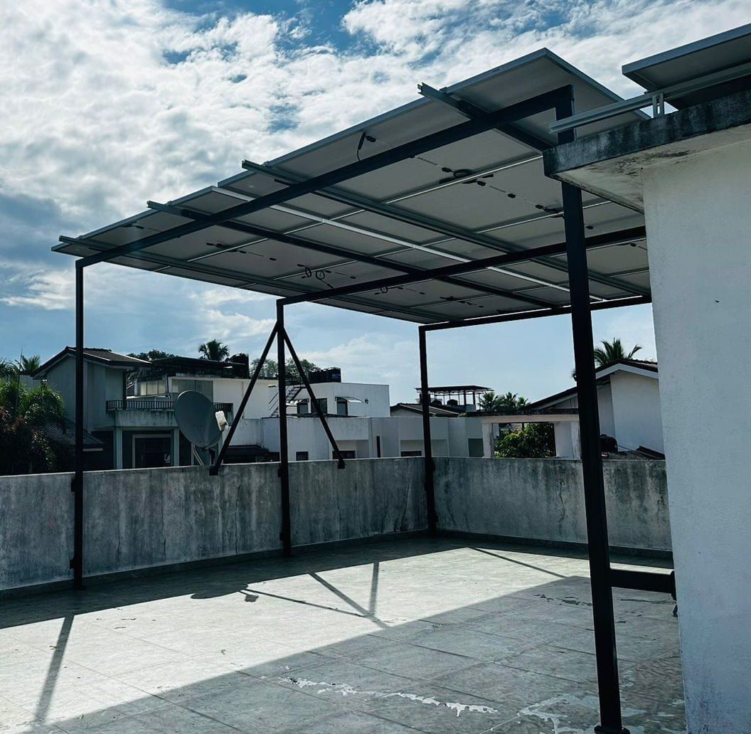 Steel frame built over a roof terrace carrying a solar array, with the terrace left usable underneath
