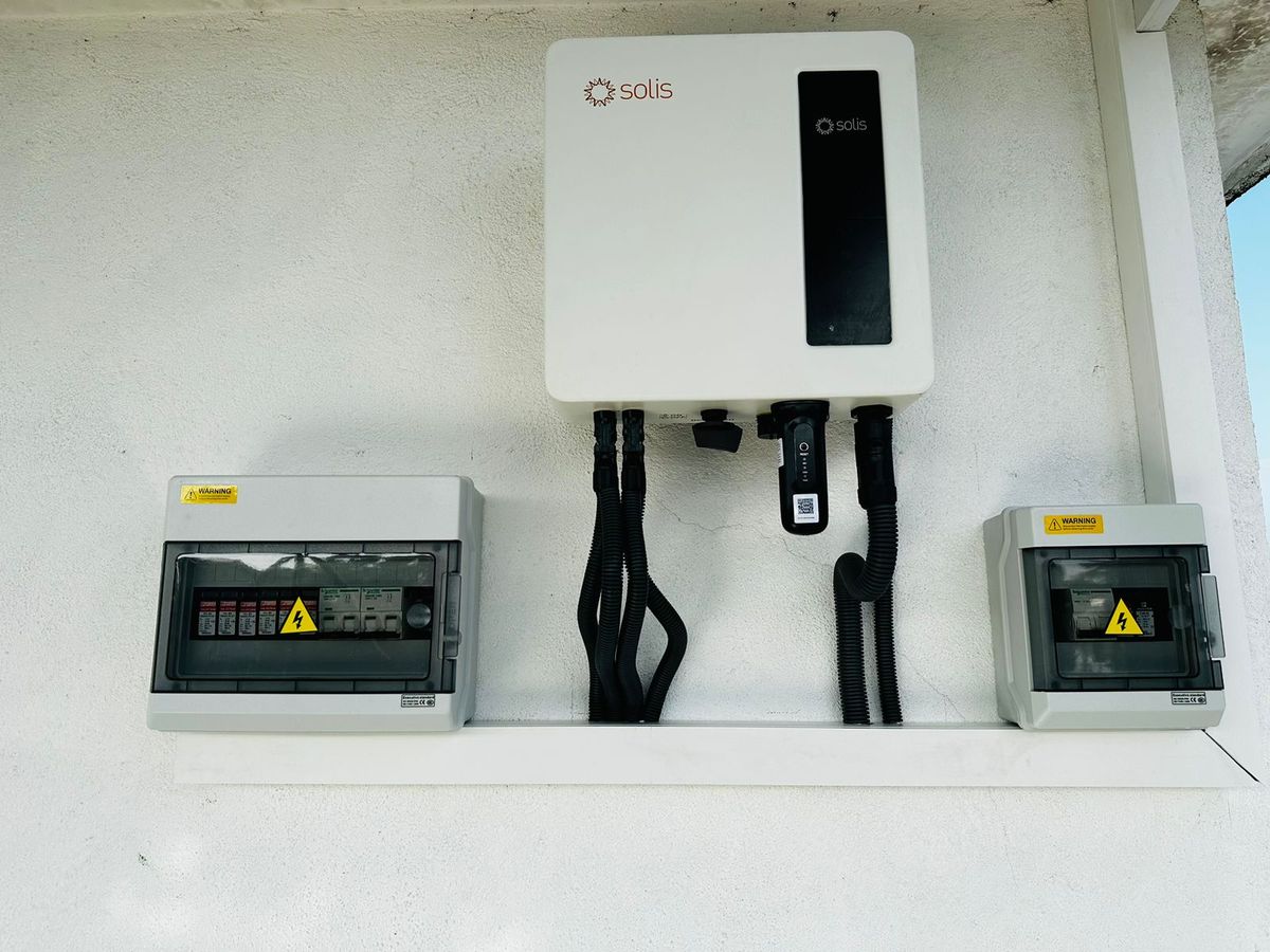 Solis grid-tie inverter mounted on a wall between two Schneider protection enclosures